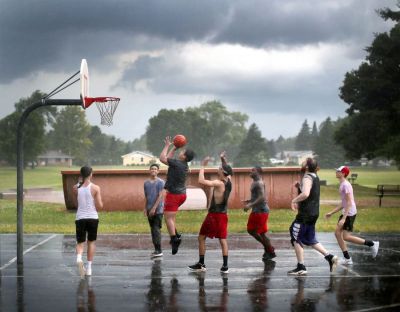 A group finishes out their basketball game in the rain as a storm begins its move through Janesville on Tuesday evening. (Anthony Wahl | Janesville (Wisconsin) Gazette)