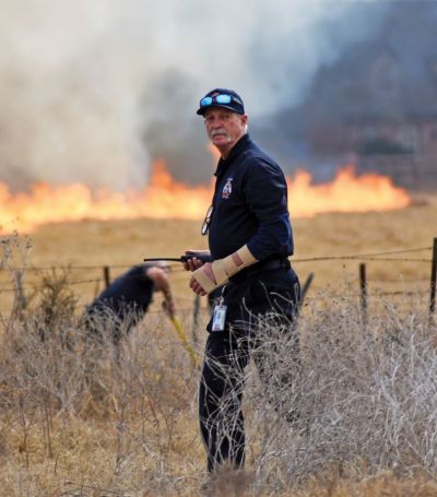 Fredericksburg Fire Chief Lynn Bizzell looks toward a fire engine that just arrived as firefighters try to stop a sizable grass fire from burning a home near Texas 16 South near Fredericksburg High School Tuesday afternoon, Feb. 22. The blaze was believed to be started by a spark after someone was cutting a fence. (Wednesday, Feb. 23, 2022) [Samuel Sutton | Fredericksburg (Texas) Standard-Radio Post]
